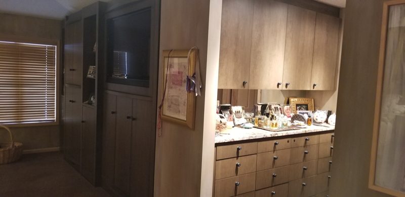 Wood built-in wardrobe cabinets beside a vanity with drawers and upper cabinets