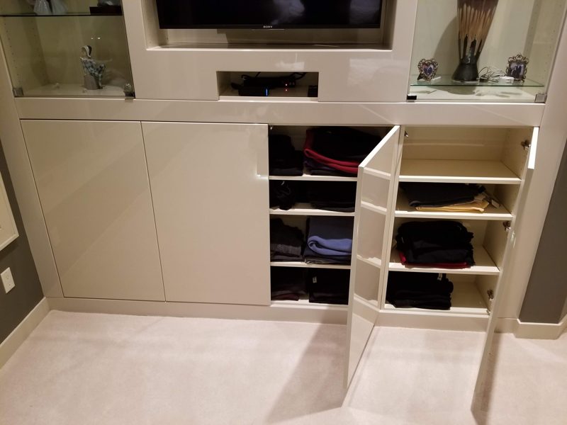 Cream built-in wall unit with doors open to reveal folded clothing shelves