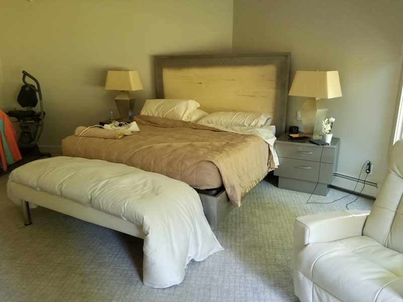 Bed with a light upholstered headboard, end-of-bed bench, and gray nightstands