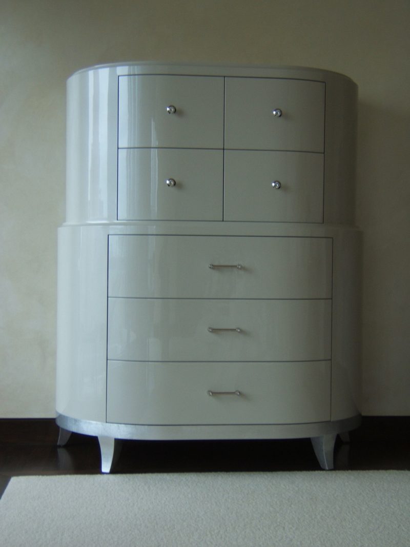 Front view of a white lacquer rounded chest of drawers with silver legs