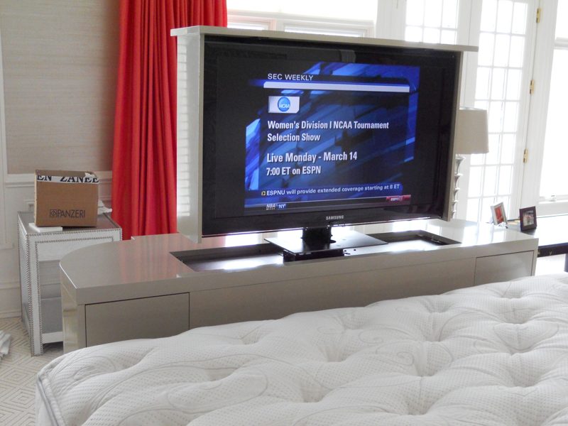 Gray TV lift cabinet viewed from the head of the bed with TV raised
