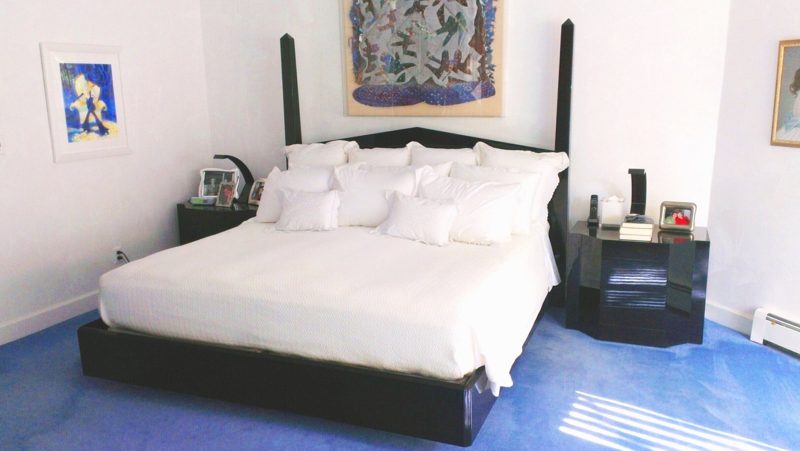 Black bed with tall black posts, white bedding, and black lacquer nightstands