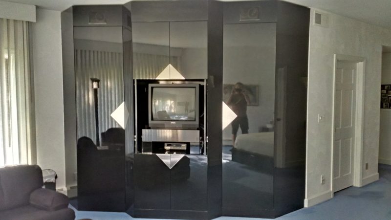 Black lacquer wall of cabinets with mirrored panels and a TV niche