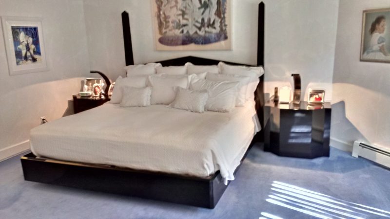 Black four-poster bed with white bedding and black lacquer nightstands