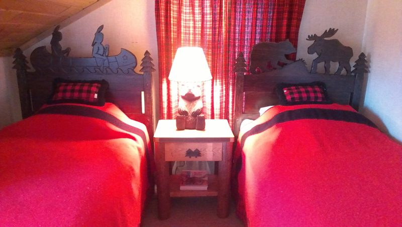 Twin beds with moose and bear cutout headboards and red bedding