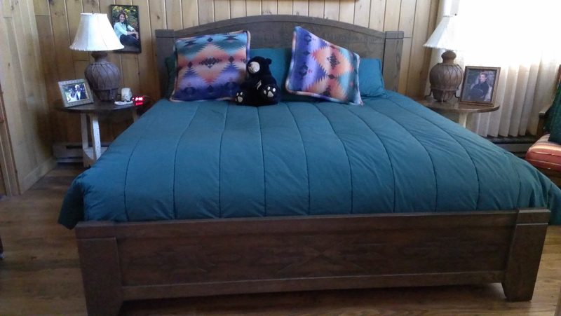 Dark wood bed with an arched headboard, teal bedding, and matching nightstands