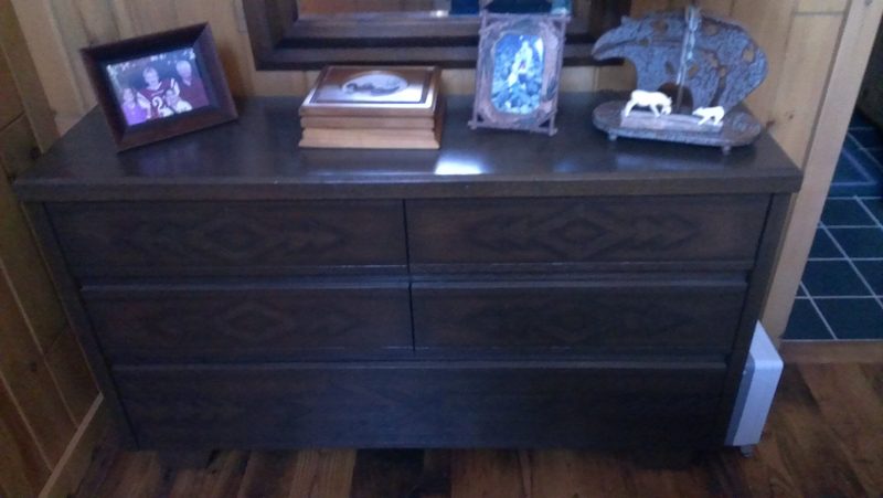 Dark wood dresser with carved diamond-pattern drawer fronts and framed photos on top
