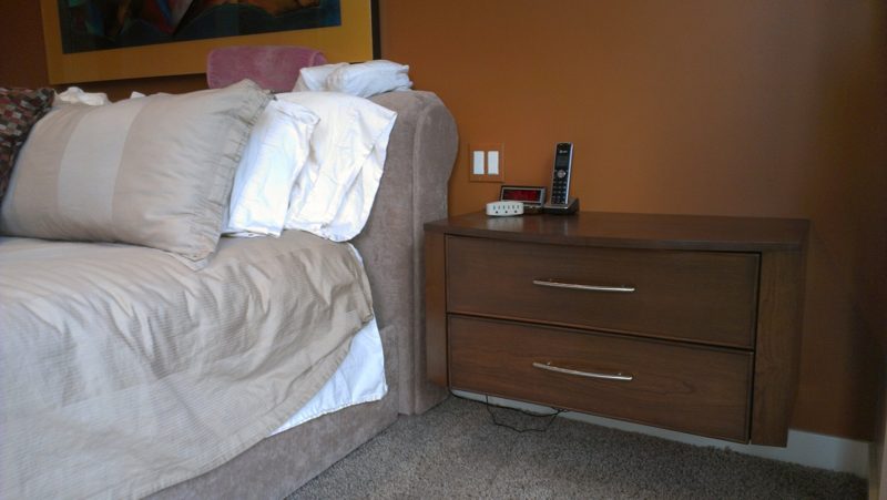 Two-drawer wood nightstand with a telephone beside a white sofa bed