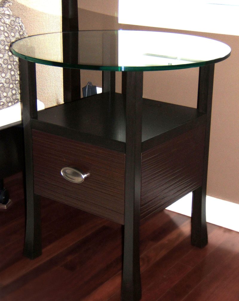 Dark wood end table with a round glass top and one drawer