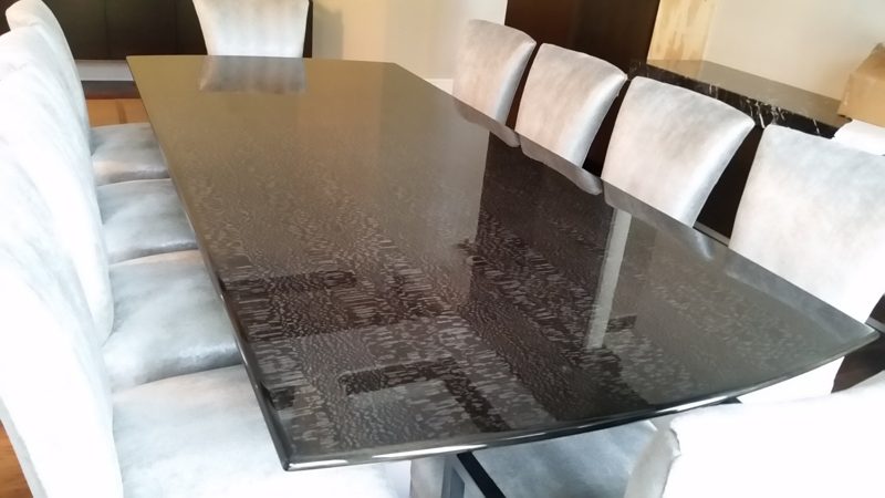 Long dark patterned glossy dining table with gray upholstered chairs