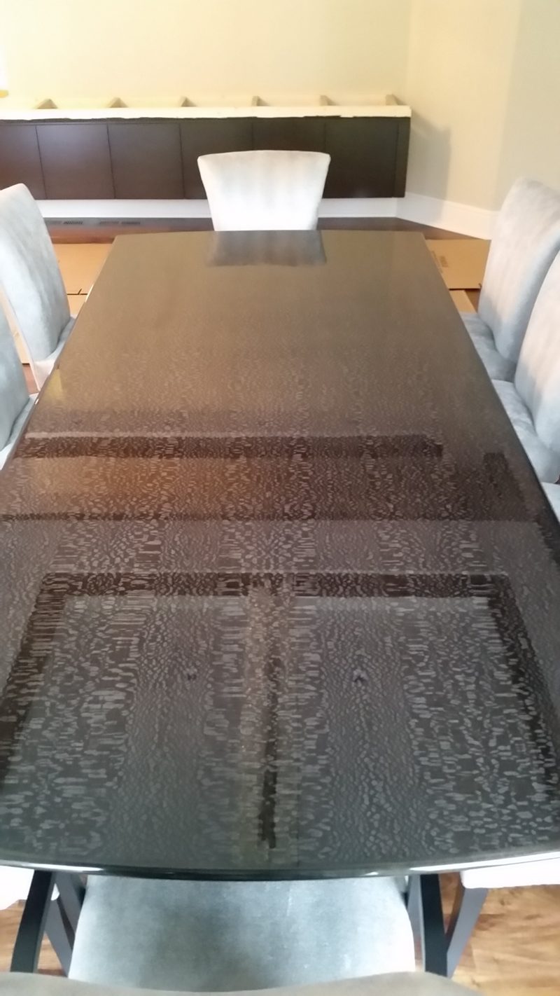 End view of a long dark patterned tabletop with a dark buffet beyond