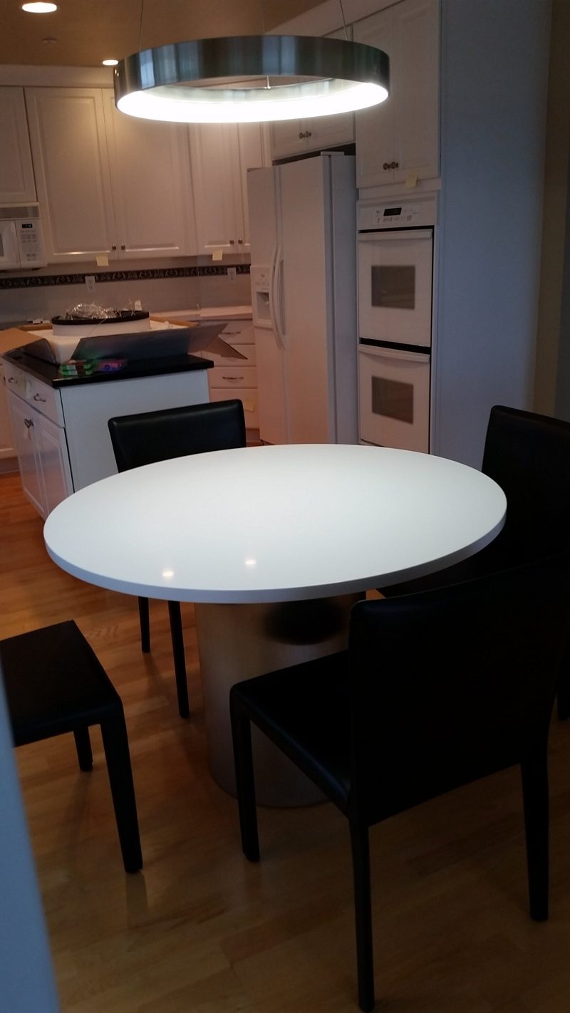 Round white dining table with black chairs in a white kitchen