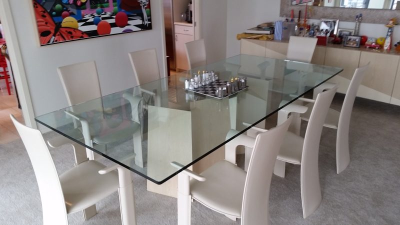 Glass-top dining table with cream high-back chairs and a matching sideboard