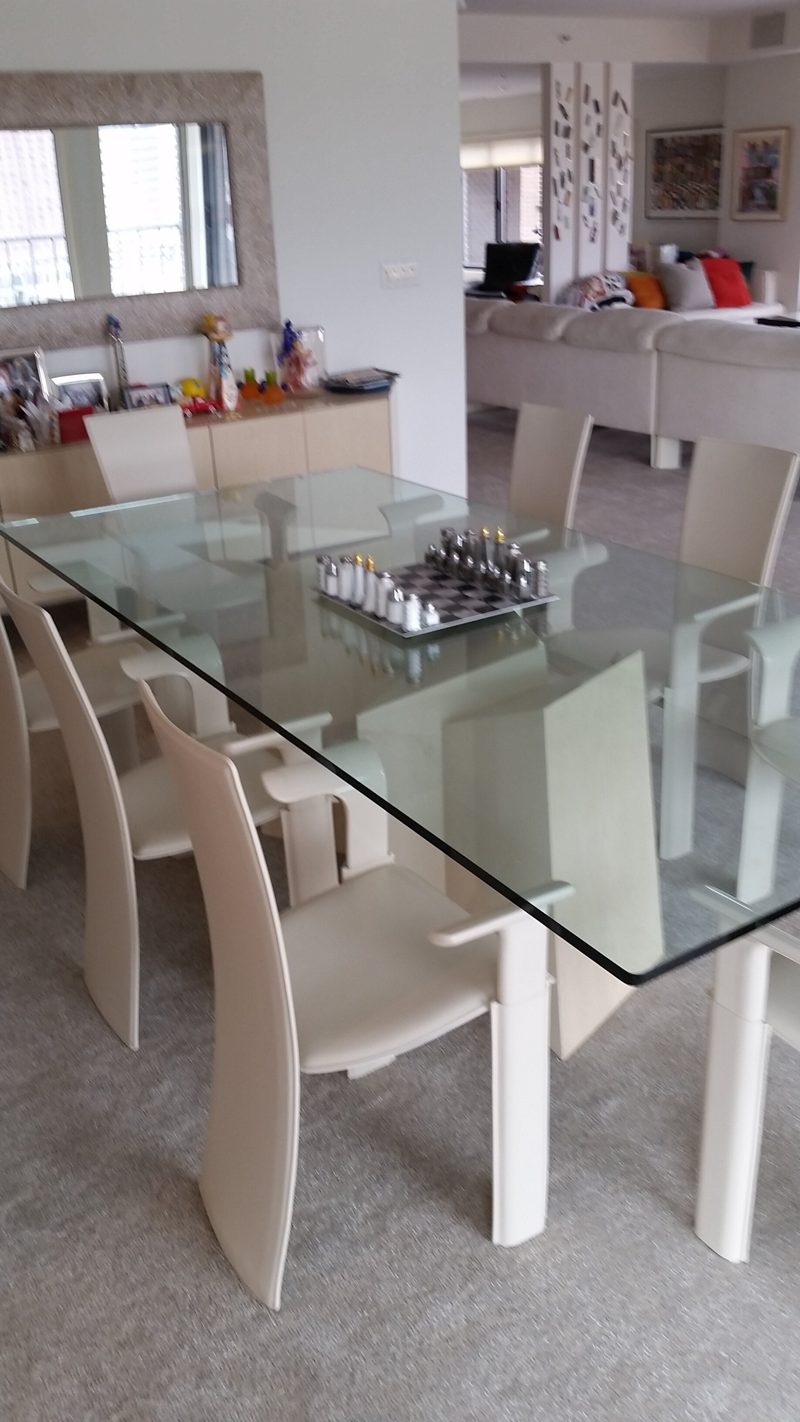 Cream high-back chairs around a glass dining table with a cream base