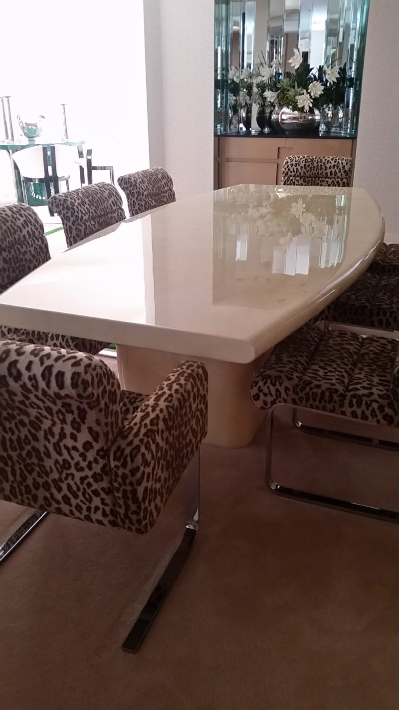Cream lacquer dining table with a tapered top and animal-print chairs