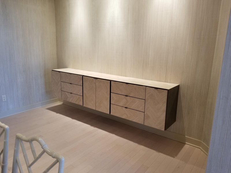 Floating light wood buffet with drawers against a paneled accent wall