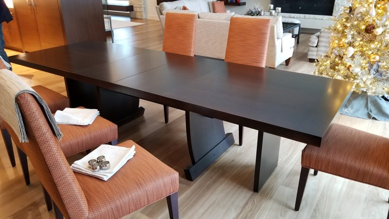 Dark wood dining table on a pedestal base with orange leather chairs