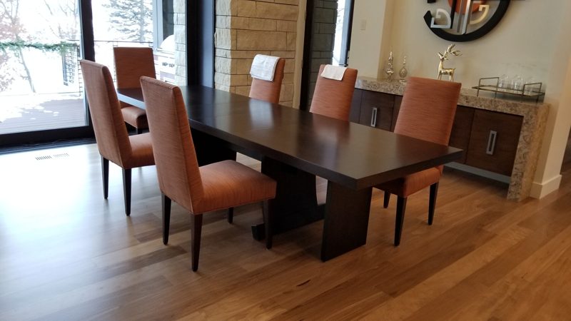 Dark wood dining table and orange chairs beside a matching dark sideboard