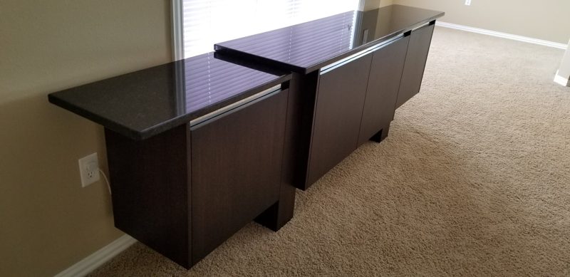Angled view of a dark wood buffet with a glossy black top