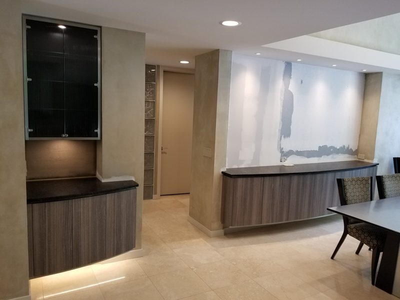 Built-in gray wood-grain buffet and lighted glass display cabinet beside dining area