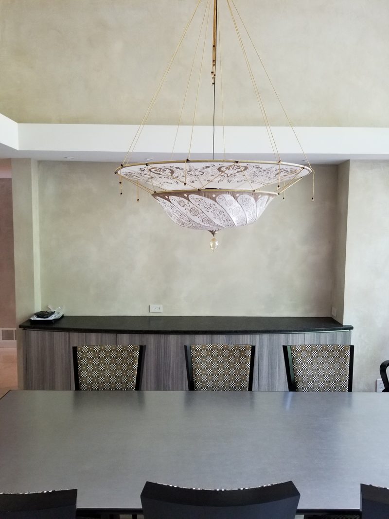 Curved gray buffet behind a dining table under a crystal chandelier