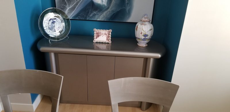 Gray metallic sideboard with rounded ends against a teal accent wall