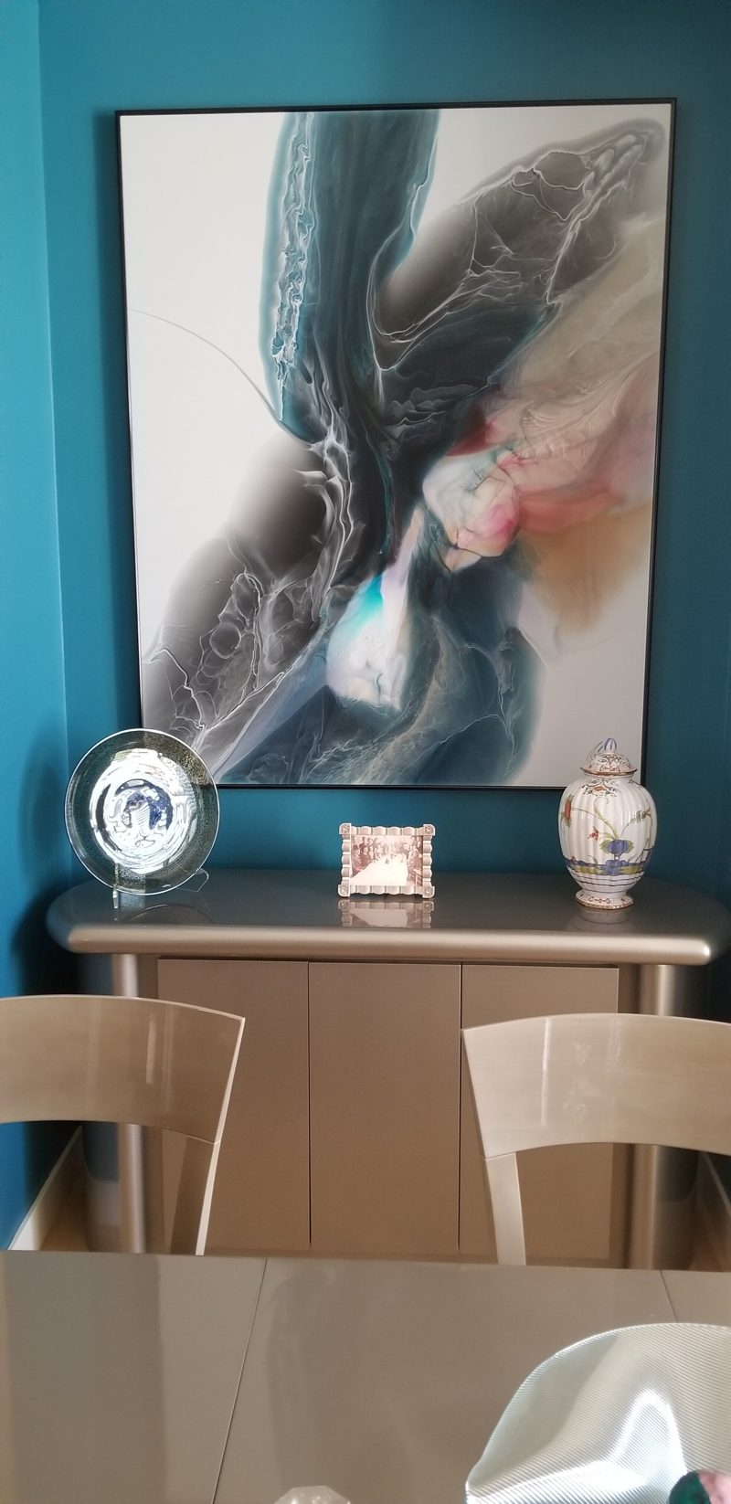 Gray rounded sideboard beneath large abstract art on a teal wall