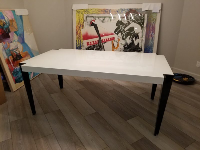 White dining table with angled black legs on a wood-look floor