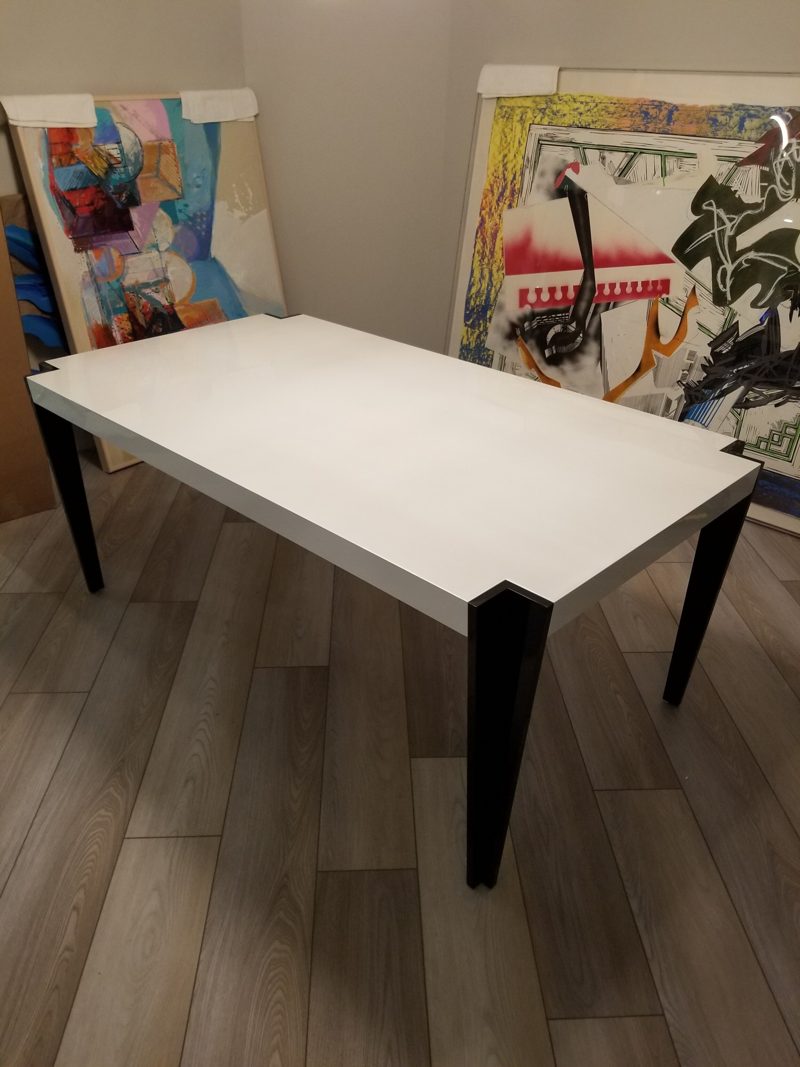 Angled view of a white dining table with tapered black corner legs