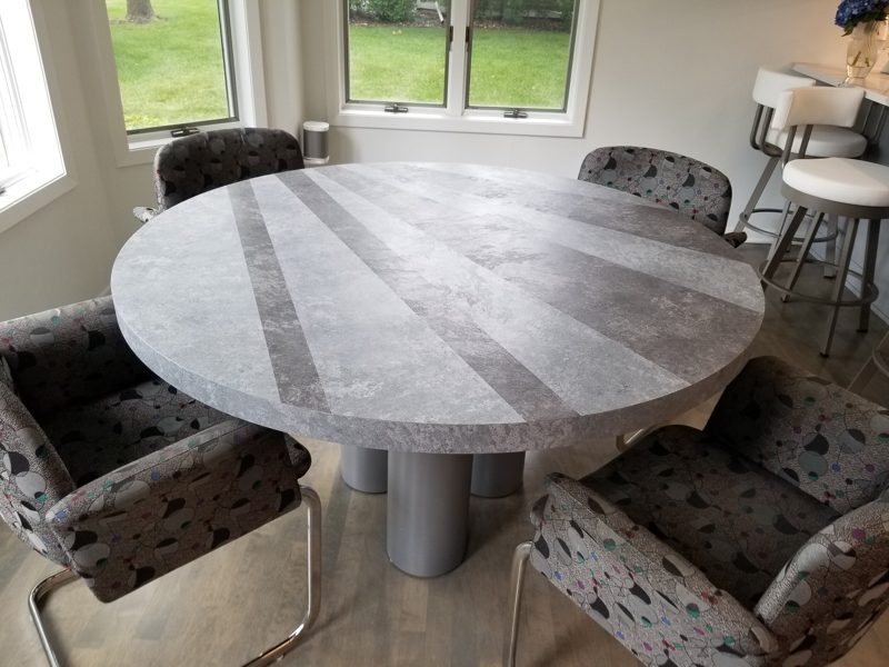 Round gray dining table with a starburst pattern top and patterned chairs