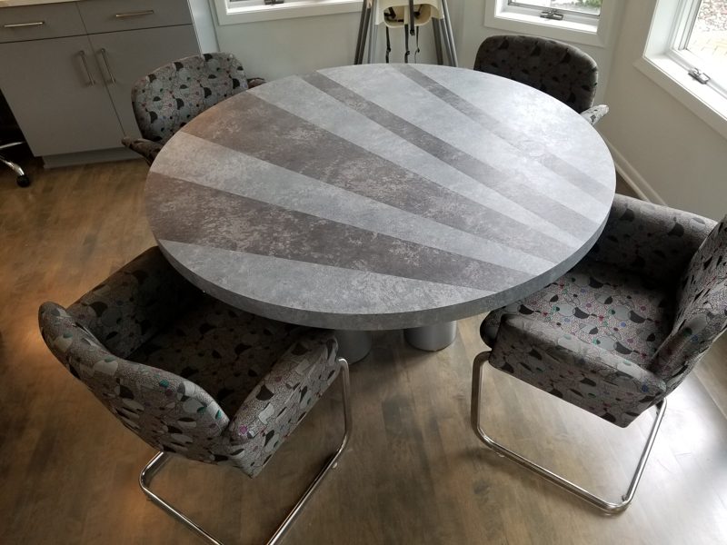 Starburst gray round dining table on a gray pedestal with chrome chairs