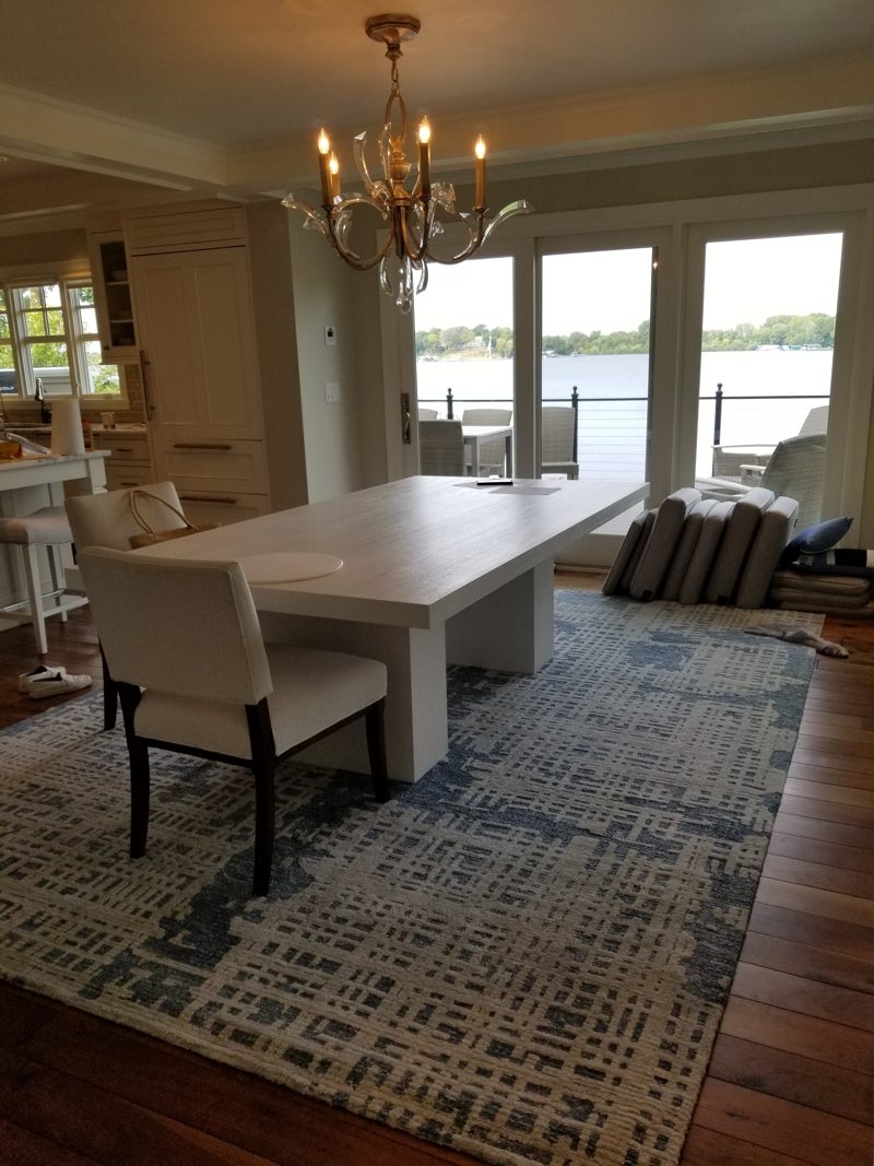 White rectangular dining table with white chairs under a chandelier