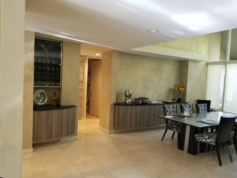 Open dining area with built-in gray cabinets and a lighted glass cabinet
