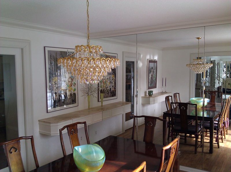 Dining room with floating cream wall consoles and a crystal chandelier