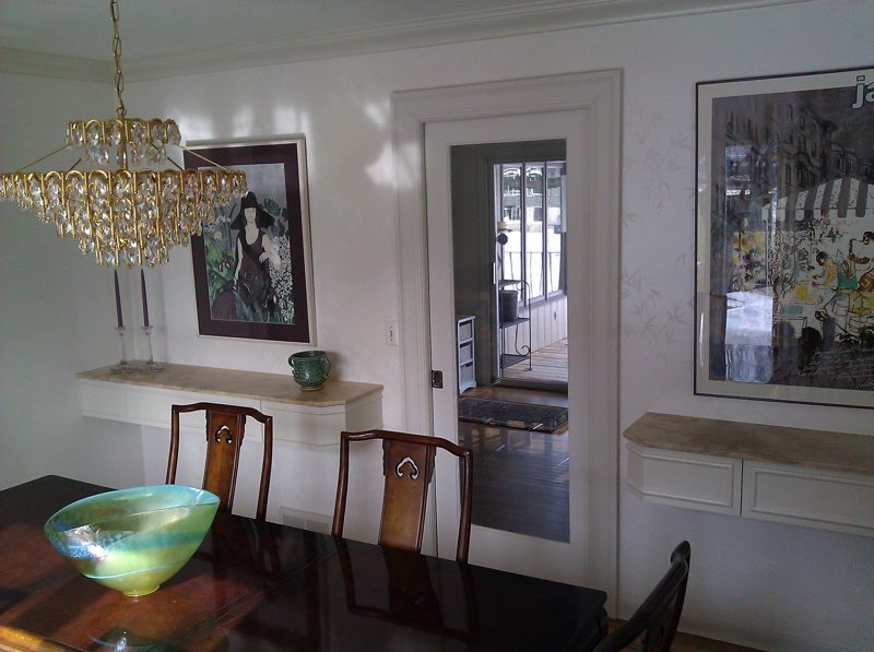 Cream floating wall consoles with stone tops beside a dark dining table