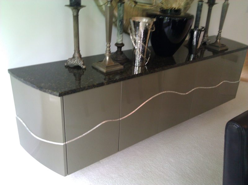Taupe floating sideboard with a curved metal inlay line and granite top