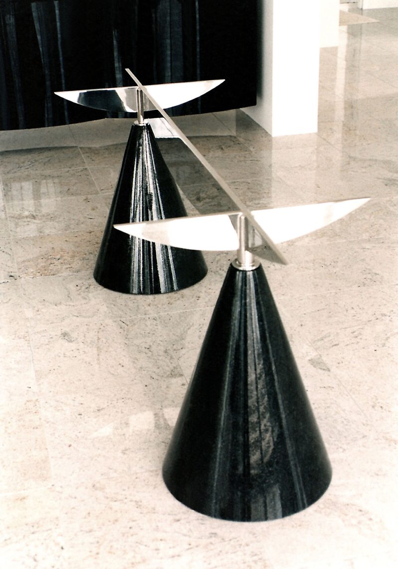 Two glossy black cone-shaped pedestal bases with angled polished metal fins