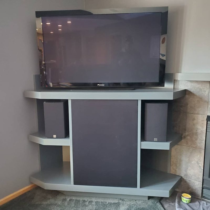 Gray corner media cabinet with a speaker panel and open side shelves