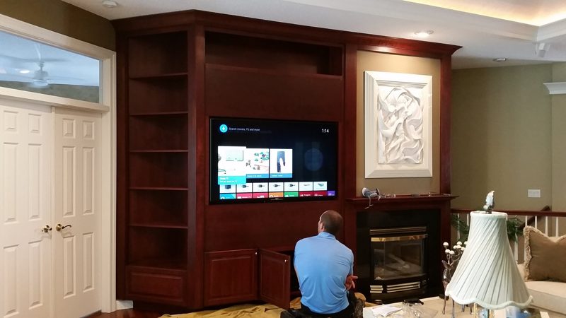 Dark cherry built-in entertainment wall with bookshelves, a TV, and a fireplace