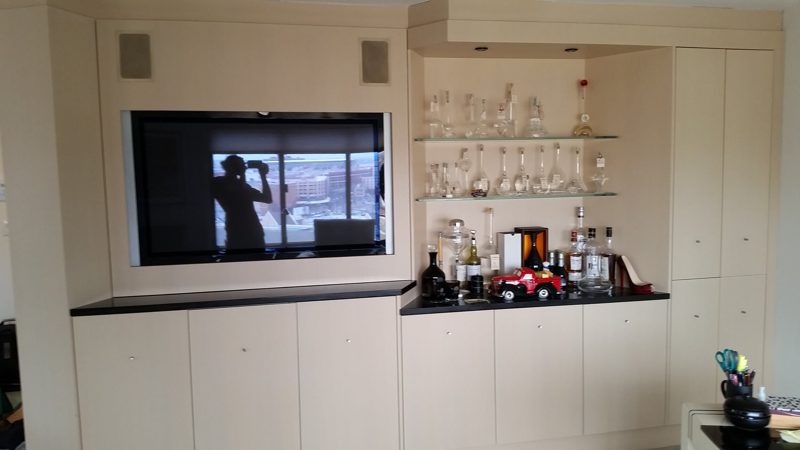 White built-in media wall with a recessed TV and glass bar shelves