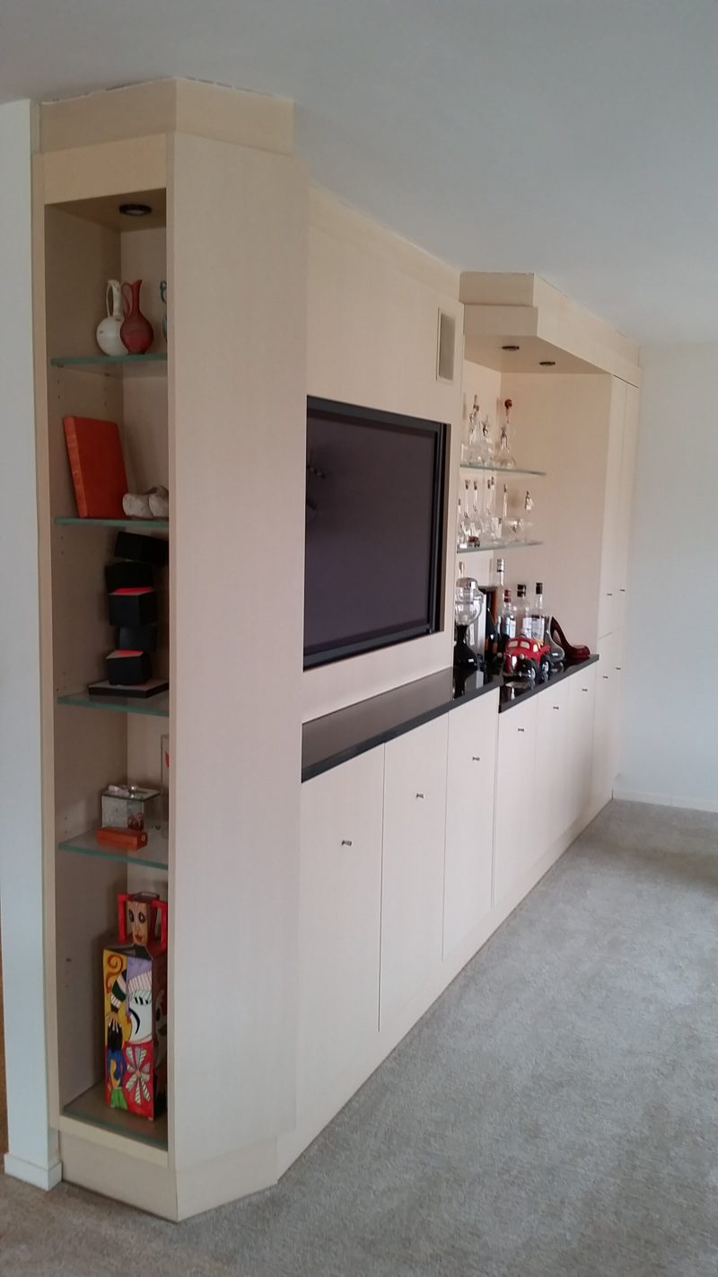 Side view of white built-ins with red-backed display shelves and a black countertop
