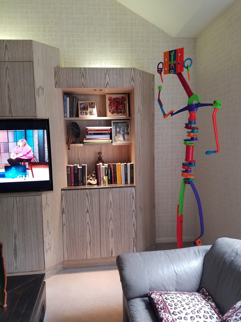 Close view of a gray wood-grain bookcase beside a colorful sculpture