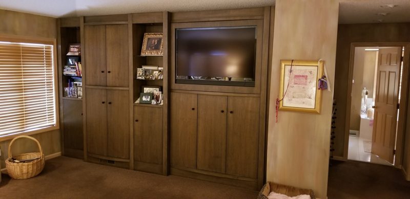 Medium wood built-in entertainment wall with cabinets, open shelves, and a TV