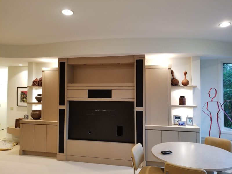 Wider view of the light wood media wall beside a round dining table
