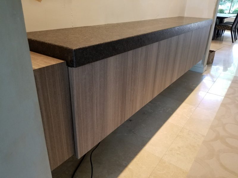 Floating gray wood-grain cabinet with a dark stone countertop