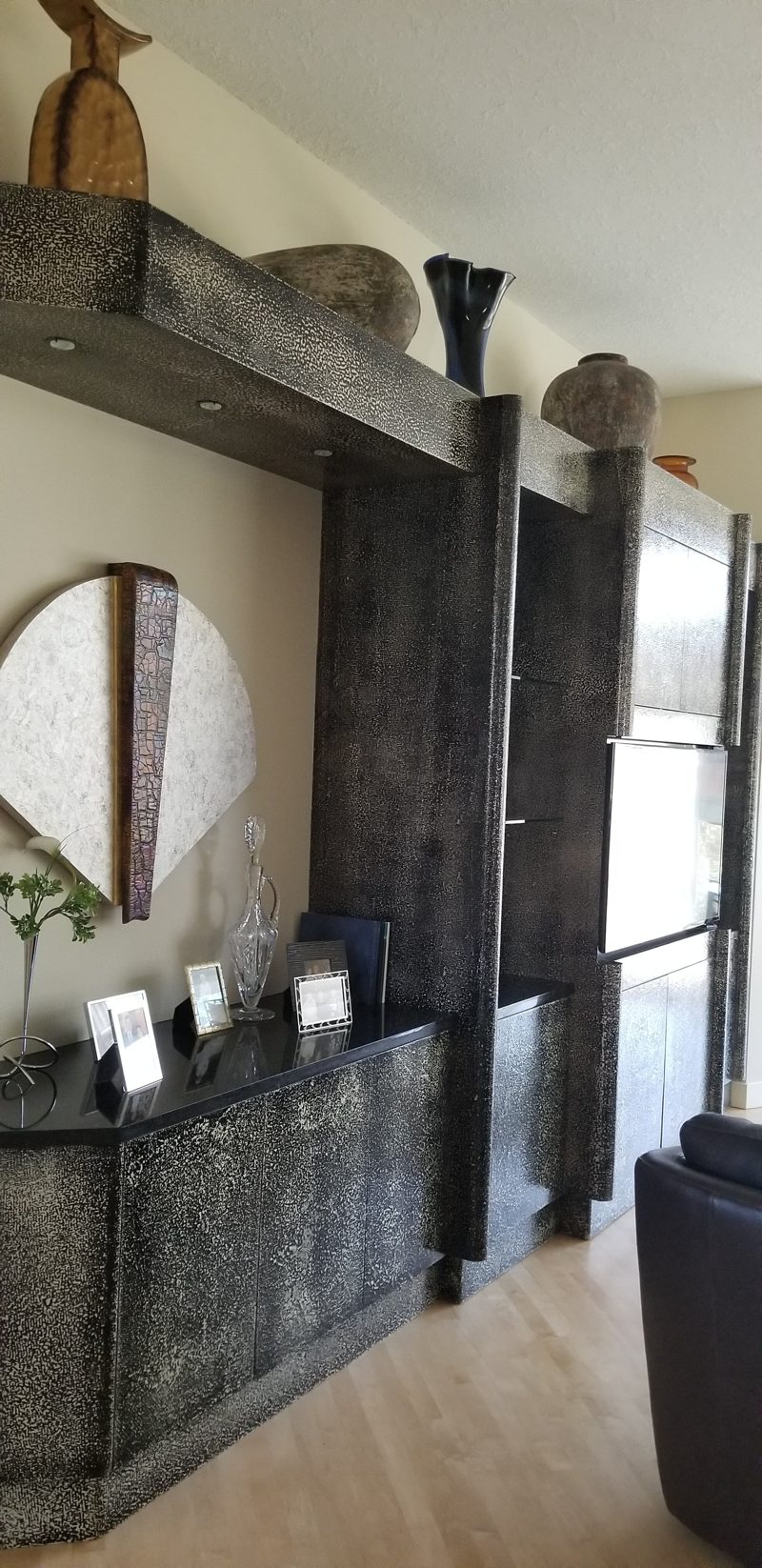 Textured dark metallic-finish media wall with open shelves and a low cabinet