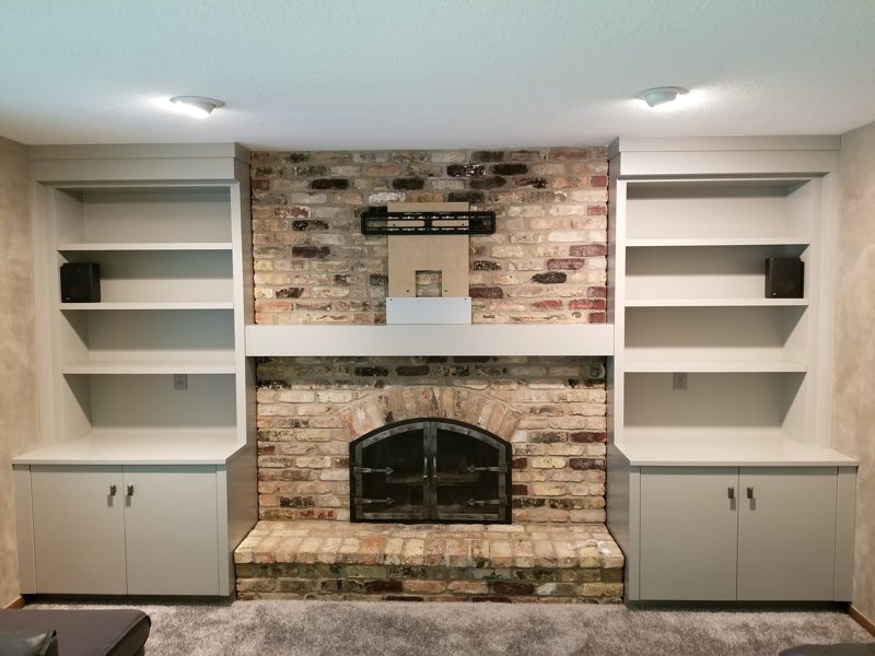 White built-in shelves and cabinets flanking a brick fireplace