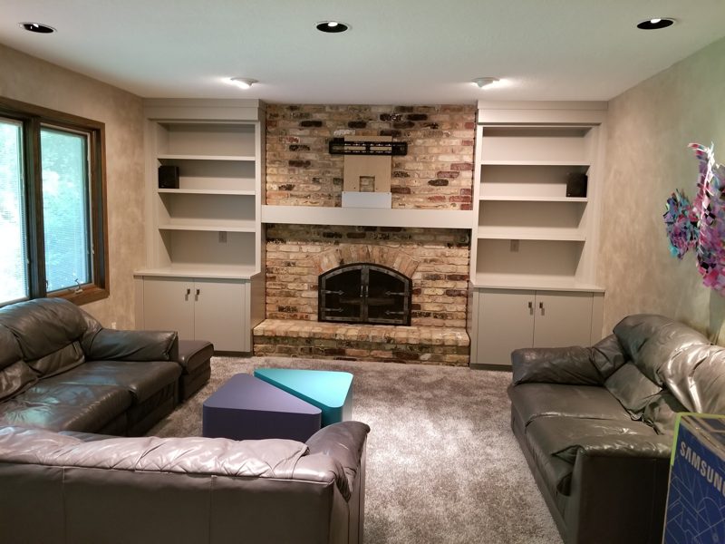 Family room with white built-ins around a brick fireplace and leather sofas