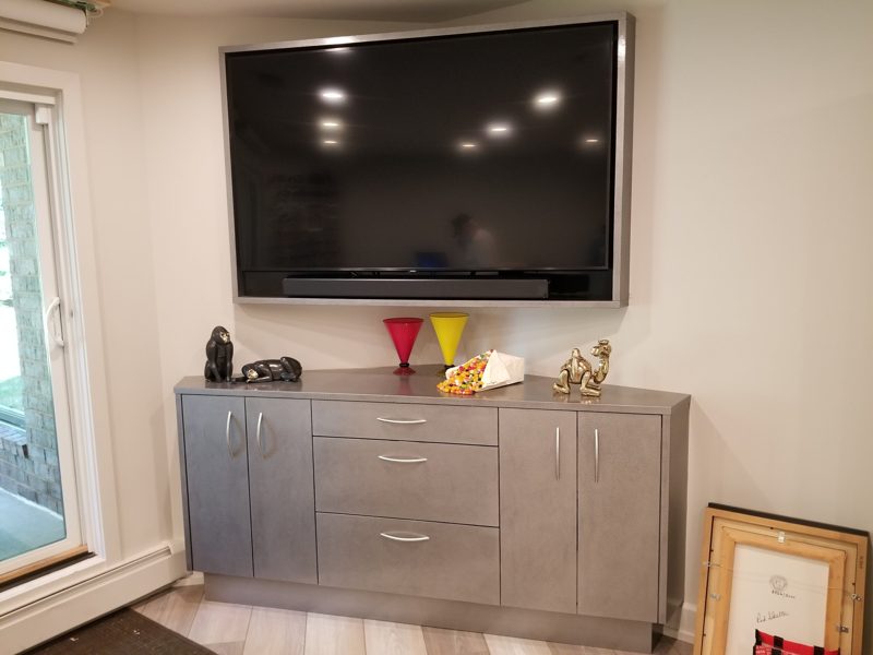 Gray cabinet with drawers and doors below a wall-mounted TV