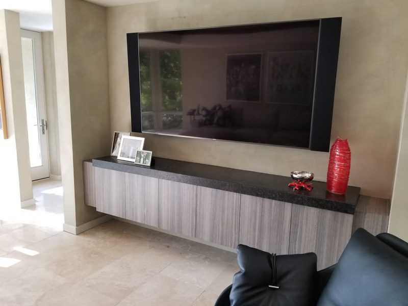 Floating gray wood-grain media console with a dark top below a large TV